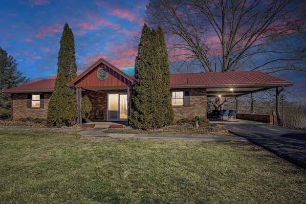 A two-story house with a brick facade, a red roof, and a covered porch.