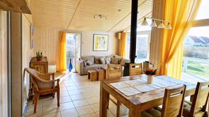 Un interior de madera acogedor con una mesa de comedor, sillas, un sofá y una chimenea.