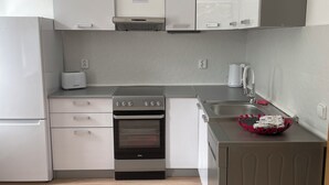 Una cucina moderna con mobili bianchi, forno integrato, tostapane e lavello.