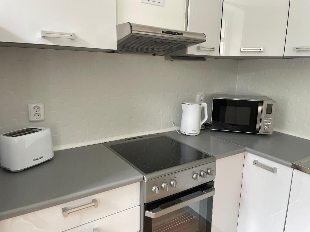 A modern kitchen with a gas stove, a microwave, a toaster, and white cabinets.