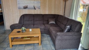 A cozy living room with a large L-shaped sectional sofa, a wooden coffee table, and a framed picture on the wall. - Ferienhaus mit Sauna im Ferienpark Mirow (Mirow)
