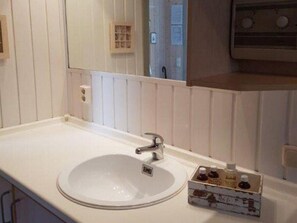 A bathroom with a white sink, a mirror, and a small cabinet with toiletries. - Ferienhaus mit Sauna im Ferienpark Mirow (Mirow)