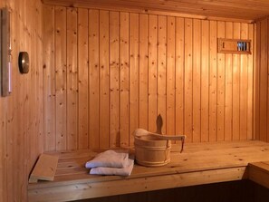 A wooden sauna room with a bench, a bucket, and towels. - Ferienhaus mit Sauna im Ferienpark Mirow (Mirow)