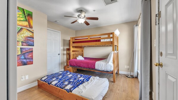 A room with two bunk beds, a ceiling fan, and a door with a chain lock. - NEW Heated Pool & HOT Tub! Ocean & pool views! (Galveston)