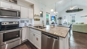 Une cuisine moderne avec des meubles blancs, des appareils en acier inoxydable et un plan de travail en granit.