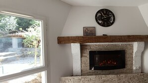 Een stenen open haard met een modern televisiescherm, een houten bovenblad en een klok erboven.