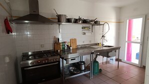 Een keuken met een fornuis, oven en diverse pannen.