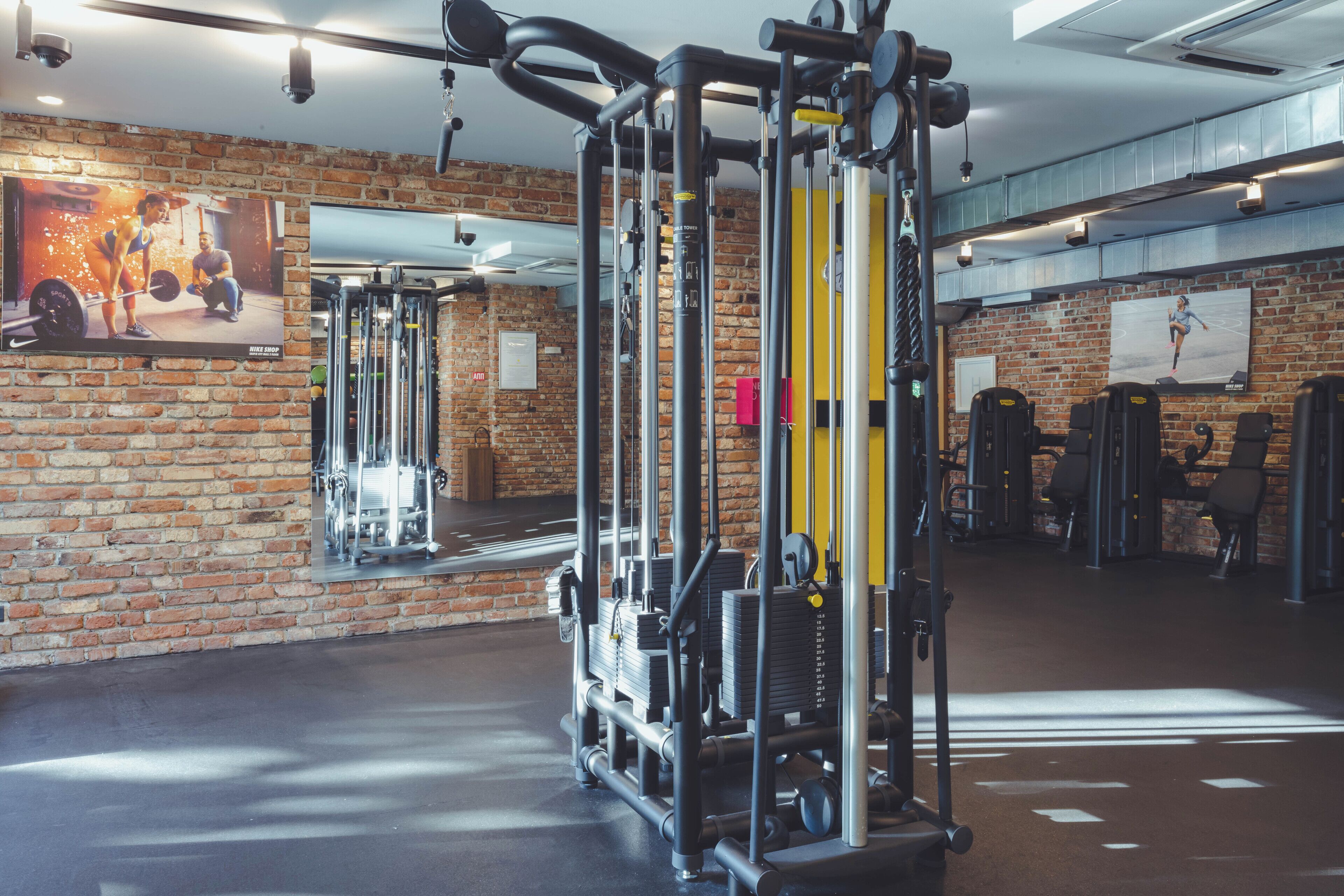 A gym with brick walls, exercise equipment, and mirrors.