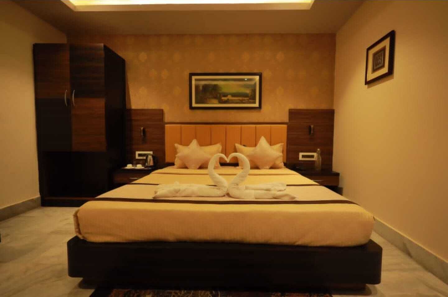 A hotel room with a large bed, two nightstands, a wardrobe, and a framed picture on the wall.
