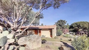 Un petit bâtiment en pierre, surmonté d’un toit en tuiles, entouré de cactus et d’arbres.