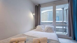 Habitación de hotel con cama, dos sillones de masaje, una ventana con vista a un balcón y cortinas.