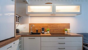 Una cocina moderna con encimera de madera, un lavabo, una cafetera y armarios.