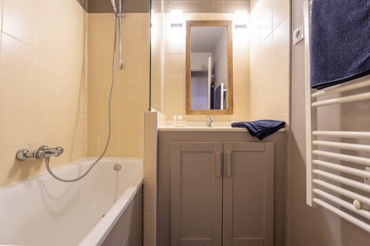 A bathroom with a bathtub, a sink, a mirror, and a towel rack.
