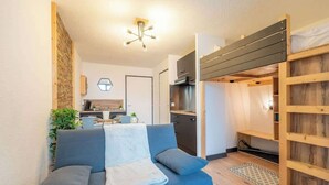 A compact living space with a sofa, kitchenette, and a small dining area.