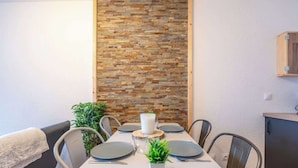 A dining area with a stone wall, a white table set for four, and a wooden cabinet to the right.