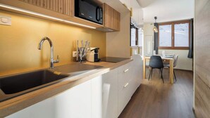 A modern kitchen with a built-in microwave, stainless steel sink, and wooden cabinets.