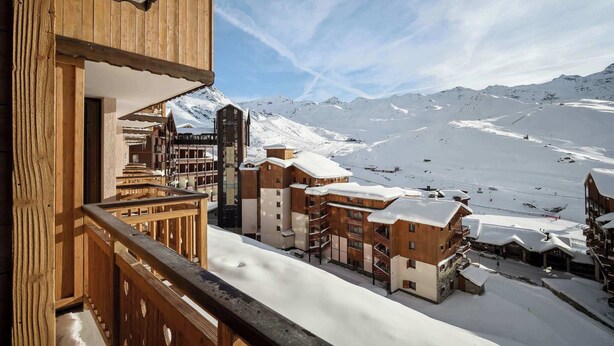 A snow-covered mountain town with wooden buildings and a ski slope in the background.
