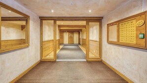 A hotel hallway with wooden walls, a carpeted floor, and a wooden reception desk with a sign.