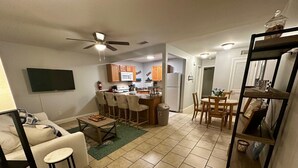 A compact living space with a kitchenette, a dining area, and a seating area with a sofa and bar stools. - Beachfront Bliss – Steps to Dining, Shops & More! (Biloxi)