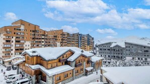 A ski resort with multi-story buildings, including a wooden lodge with a snow-covered roof.