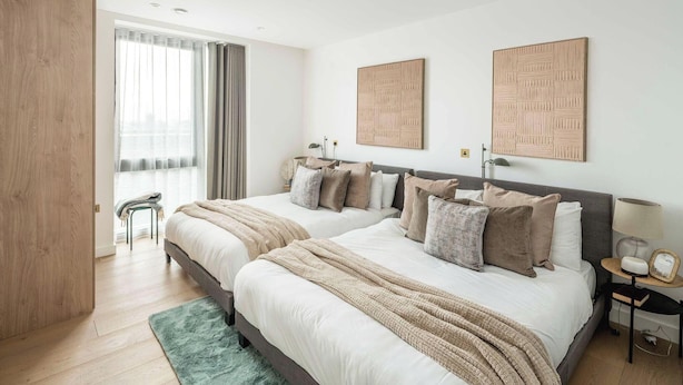 Une chambre moderne avec deux lits, une grande fenêtre avec des rideaux et un tapis vert.