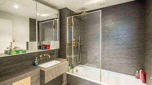 Une salle de bain moderne avec deux lavabos, une douche à parois de verre et un grand miroir.