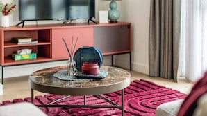 Un salon avec une table basse ronde, un téléviseur et un canapé rouge.