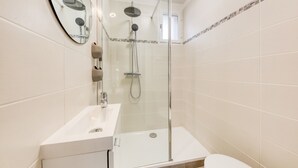 A modern bathroom with a glass-enclosed shower, a white sink, and a toilet. - Cocoon - garden - Key box - Wifi (Baulne)