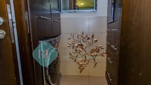Un pasillo estrecho con un cuadro decorativo de un árbol, armarios de madera y una ventana al final.