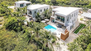 A modern two-story house with a swimming pool, surrounded by lush greenery and a golf course in the background. - Lotus Villas #1-Leeward Palms. Your Gateway to Paradise & Step into Serenity.... (Leeward Settlement)