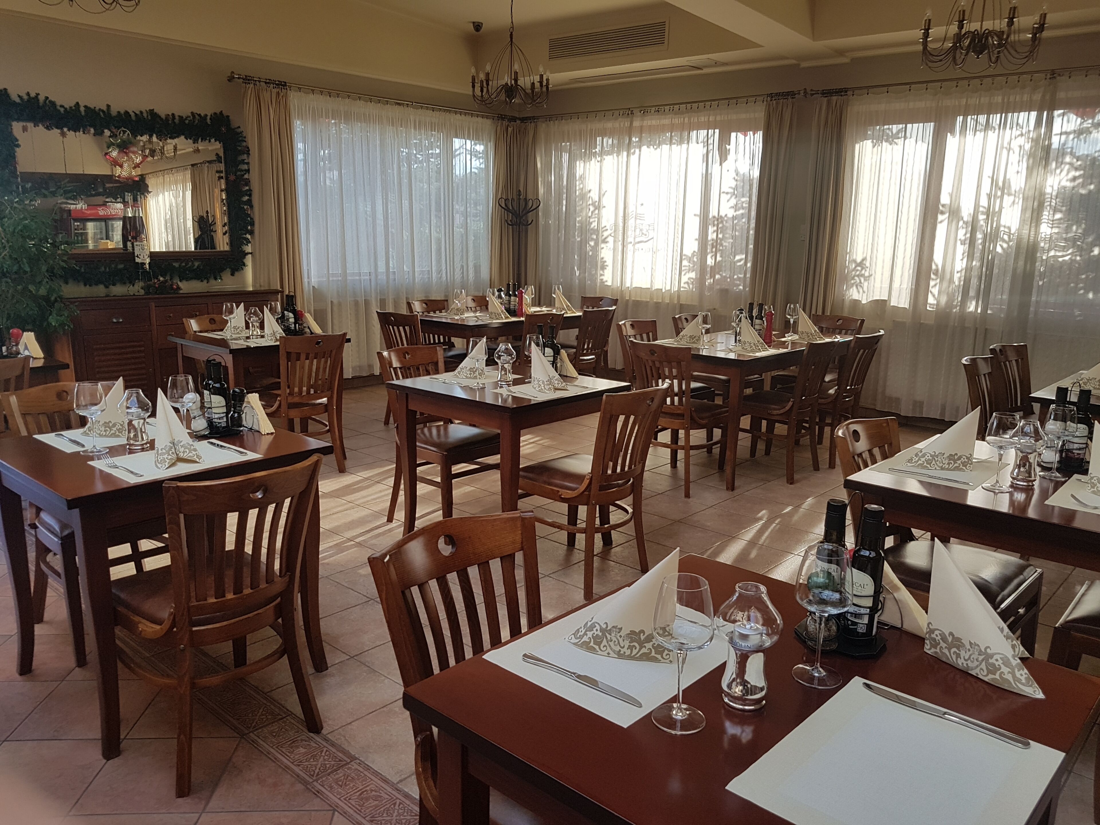 Un comedor con varias mesas dispuestas para una comida, sillas de madera y una araña.