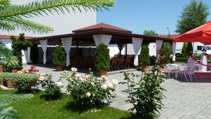 Eine Außenpatio-Terrasse mit überdachter Sitzgelegenheit, Topfpflanzen und Gartenmöbeln.