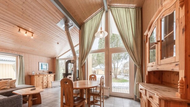 Interior de una cabaña de madera con comedor, cocina y zona de estar.