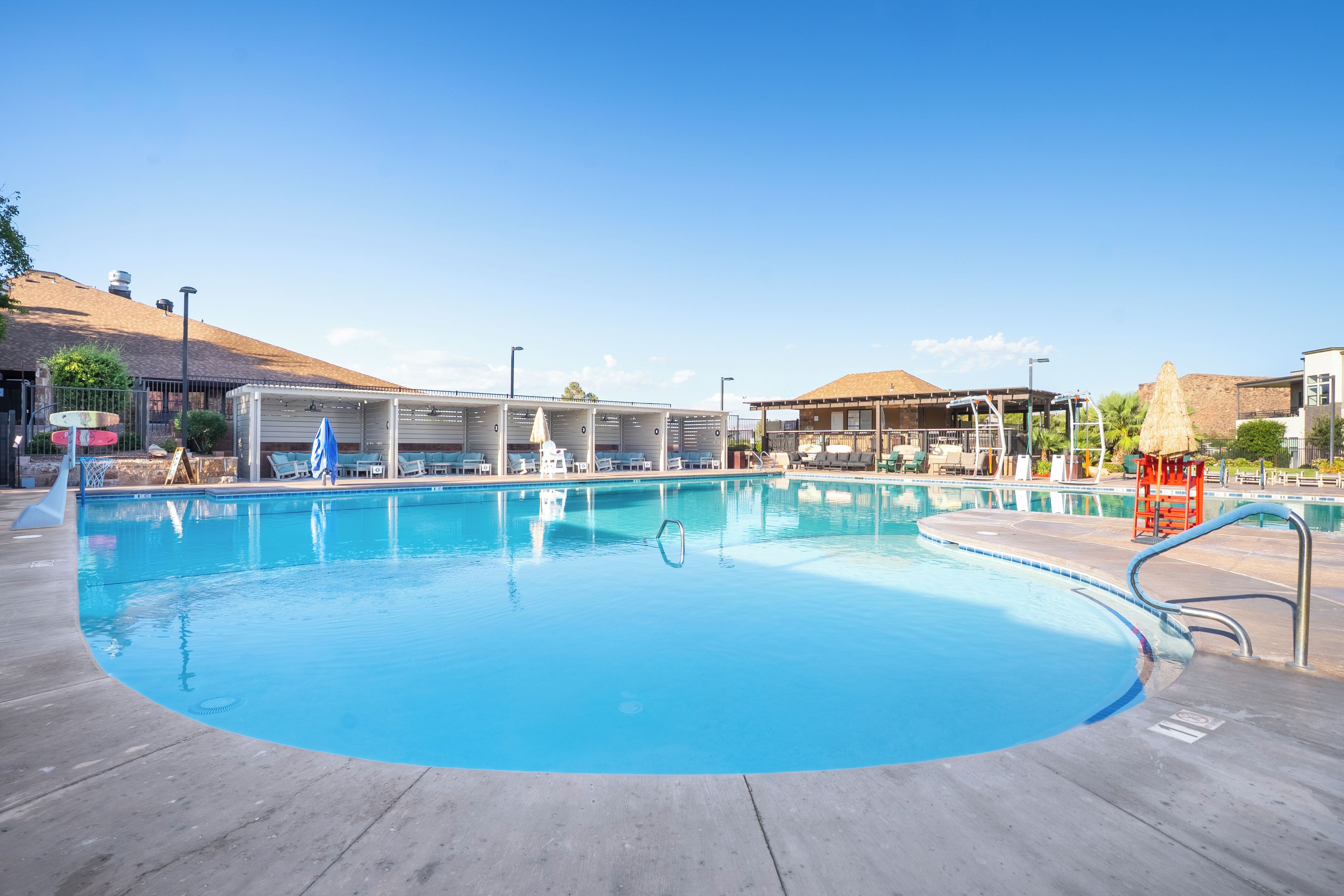 Une piscine à l’eau d’un bleu cristallin, entourée de chaises longues et de parasols.
