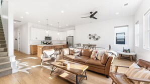 A spacious living area with a wooden coffee table, leather sofa, and a kitchen in the background. - Villa #17 at Bloomington Country Club: Pool, Golf, Restaurant (St. George)