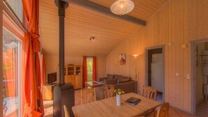 A cozy wooden interior with a dining table, chairs, a sofa, and a TV. - Ferienhaus mit Sauna im Ferienpark Mirow (Mirow)