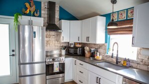 A modern kitchen with stainless steel appliances, white cabinetry, and a brick accent wall. - Stylish & Romantic with Hot Tub (Loveland)