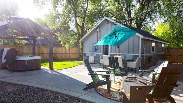 An outdoor patio with a hot tub, seating area, and a covered space with a table and chairs. - Stylish & Romantic with Hot Tub (Loveland)