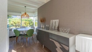 A modern kitchen with a white countertop, green chairs, and a hanging light fixture. - Bungalow in Sint Maartenszee Near Beach (Sint Maartensvlotbrug)