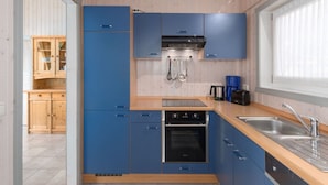 Una cocina moderna con armarios azules, un lavamanos de acero inoxidable y un horno empotrado.