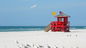 A red lifeguard tower with a flag on a sandy beach. - IMG, Bradenton Beach, Anna Maria, Siesta Key Beach Beautiful & Centrally Located (Sarasota)