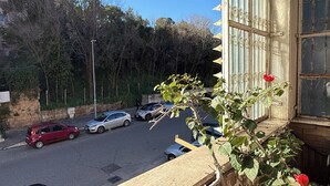 A view from a balcony overlooking a street with parked cars and trees in the background. - Apartment in the heart of EUR (Roma)