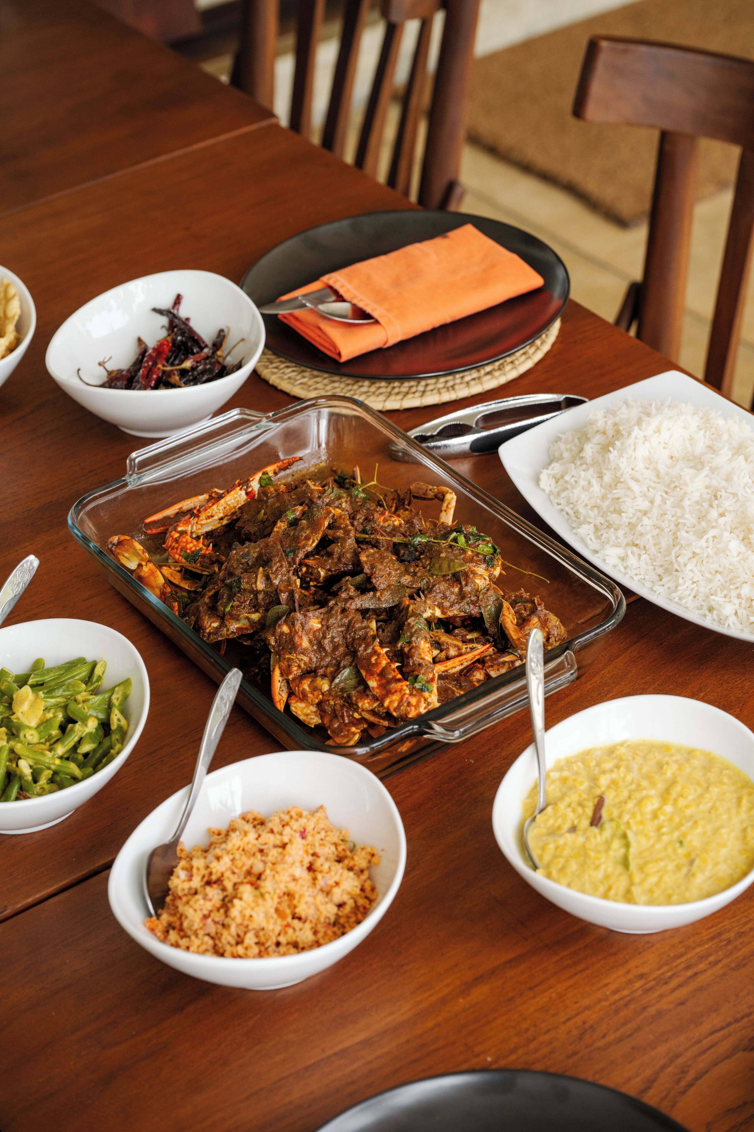 A dining table with various dishes including rice, a glass dish with meat, and several bowls of side dishes.
