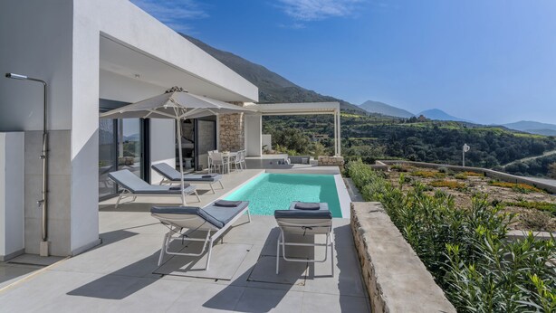 Ein moderner Poolbereich im Freien mit Liegestühlen und Blick auf die umliegende Landschaft.