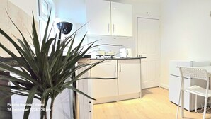 Una cocina moderna con armarios blancos, una estufa y un comedor con una silla y una mesa blancos.