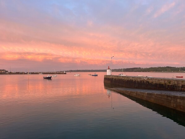 A harbor at sunset with calm water, boats, and a lighthouse. - Sous Le Phare (Louannec)