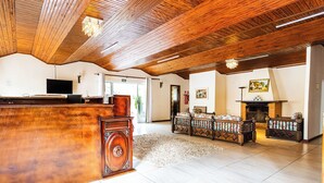 Un salón amplio con techo de madera, chimenea y televisor.