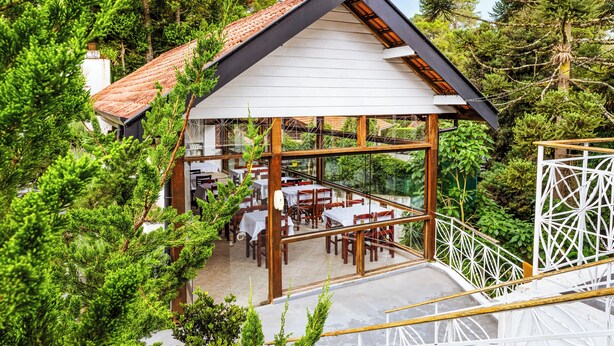 Un restaurante con terraza al aire libre, rodeado de árboles.
