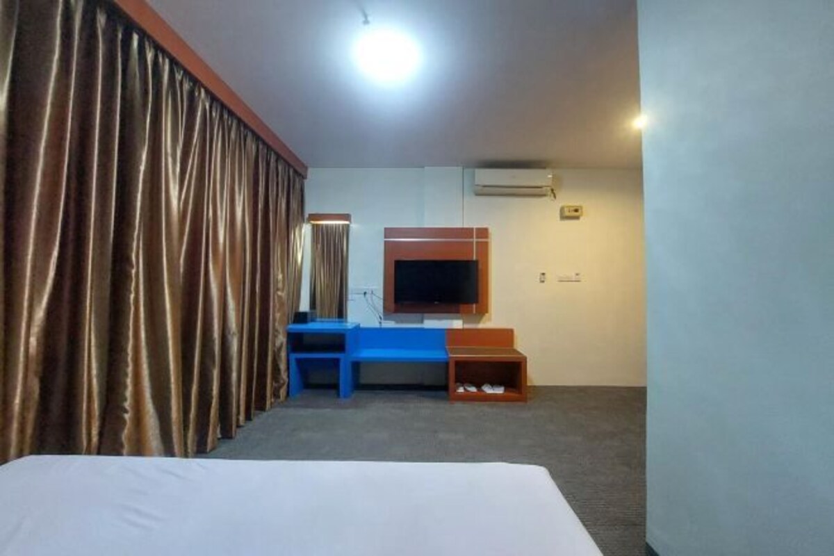 Ein Hotelzimmer mit Bett, Fernseher, Schreibtisch und Kleiderschrank.