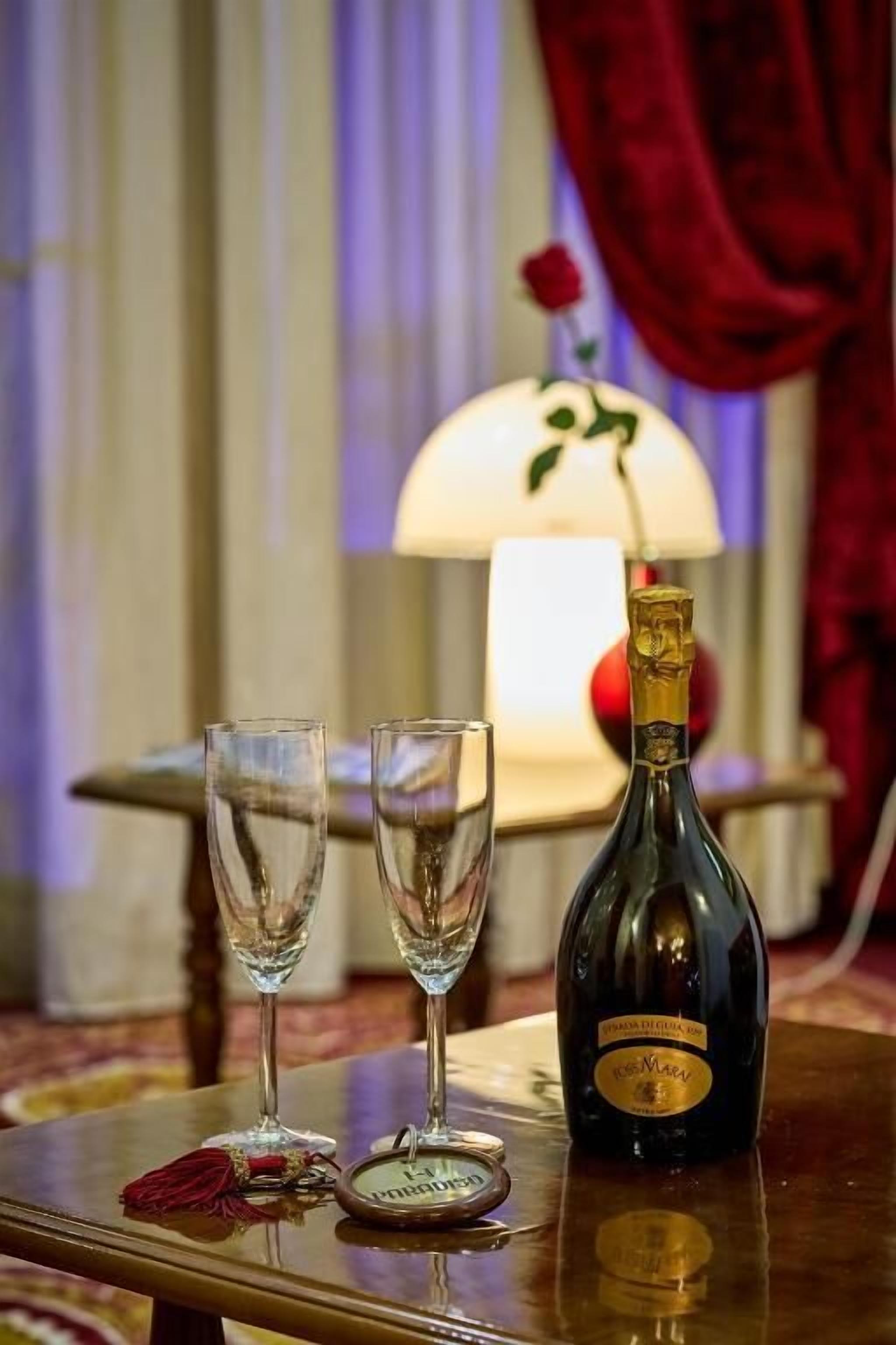 A bottle of champagne and two glasses on a table with a decorative item and a keychain.